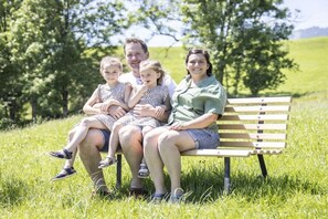 A family of four on a wooden bench in a grassy field with trees in the background. - Holiday apartment in Egg with swimming pool (Egg)