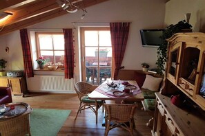 A dining area with a table, chairs, and a television mounted on the wall. - Holiday apartment with 2 bedrooms (Hochkrimml)