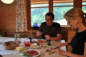 Un interior de madera con una mesa dispuesta para una comida, incluyendo platos de comida, una jarra y botellas.