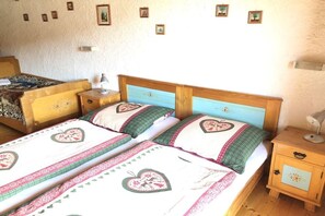 Un letto matrimoniale con copripiumino floreale e due cuscini, un comodino con una lampada, e una piccola cassettiera con uno specchio.