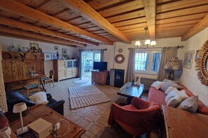 Un accogliente soggiorno con soffitto in legno, un divano, un tavolino e una televisione.