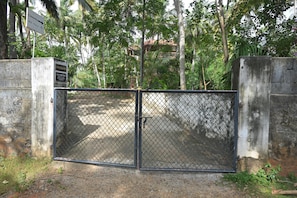 A gated entrance with a metal fence, a signboard, and a concrete wall. - Relaxing Holiday Villa in Santhapuram, Kanyakumari (Nagercoil)