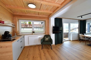 Een modern interieur met een houten plafond, een keuken, een eethoek en een televisie.
