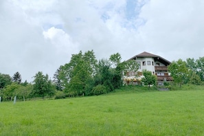 A multi-story building with a sloped roof, surrounded by a grassy field and trees. - Irrsee Mondseeland Salzkammergut (Oberhofen am Irrsee)