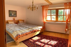 A bedroom with a wooden bed, a large window with curtains, a chandelier, and a painting on the wall. - Irrsee Mondseeland Salzkammergut (Oberhofen am Irrsee)