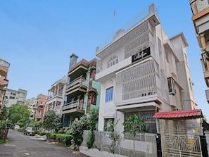 Un edificio residencial de varios pisos con balcones, una entrada porticada y un cielo despejado.