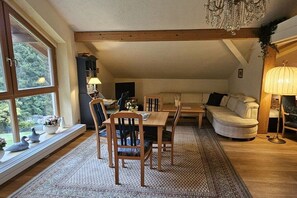 A cozy living room with a dining area, a sofa, and a chandelier. - Holiday apartment with 1 bedroom (Feldkirchen in Kärnten)