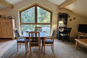 A dining area with a large window, wooden furniture, and a view of trees. - Holiday apartment with 1 bedroom (Feldkirchen in Kärnten)