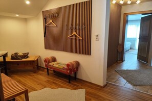 A room with a wooden slat wall, a red sofa, a wooden table, and a hanging coat rack. - Apartment in Ehrwald with swimming pool (Ehrwald)