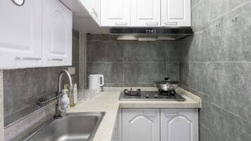 Una cocina moderna con armarios blancos, un lavamanos de acero inoxidable, una estufa a gas y una cafetera.