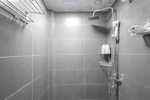 Een moderne douchekamer met een handdouche, een wandhaardroger en een plank met toiletartikelen.