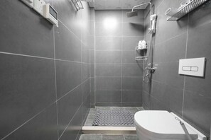 Een compacte, moderne badkamer met douche, toilet en een bedieningspaneel aan de muur.