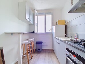 A compact kitchen with a window, a gas stove, and a trash bin. - Quiet apartment on the 4th floor (Saint-Brieuc)