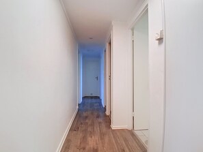 A narrow hallway with wooden flooring and white walls, leading to a door at the end. - Quiet apartment on the 4th floor (Saint-Brieuc)