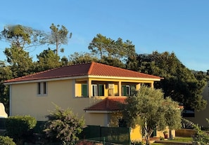 Un edifici de dues plantes amb teulada vermella, envoltat de vegetació i arbres.