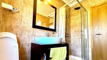 A bathroom with a toilet, sink, mirror, shower, and a towel rack.