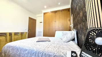 A hotel room with a bed, a wooden wardrobe, a radiator, and a power outlet.