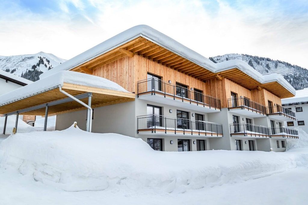 A multi-story building with wooden balconies and a snow-covered landscape.