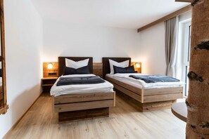 Ein Zimmer mit zwei hölzernen Betten, jeweils mit Kopfteil, Nachttischen und Wandlampen.