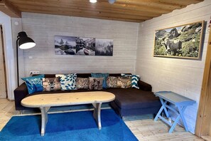 A cozy room with a wooden ceiling, a sofa with patterned cushions, a coffee table, and a framed picture on the wall. - Holiday home in Rauris with sauna (Rauris)