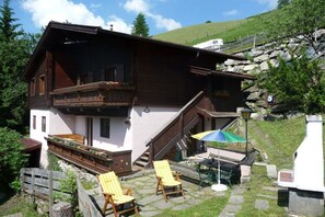 Eine Chalet mit Balkon, Sitzgelegenheit im Freien und einer Steintreppe.