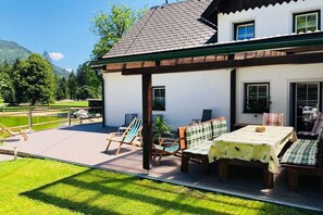 Ein Haus mit Terrasse, Sitzgelegenheiten im Freien und Blick auf eine grüne Landschaft.