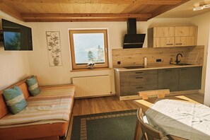 A cozy room with a bed, a small table, a window with a view, a kitchenette, and a radiator. - Holiday apartment with 2 bedrooms (Hart im Zillertal)