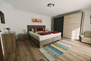 A bedroom with a bed, bedside tables, a wardrobe, a sofa, and a large window. - Holiday apartment with 2 bedrooms (Hart im Zillertal)