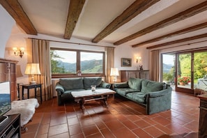 Ein gemütliches Wohnzimmer mit Holzboden, zwei grünen Sofas, einem Couchtisch und einem Fernseher.