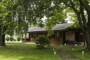 A lodge with a wooden exterior, a covered porch, and a well-maintained lawn. - Holiday alpine house (St. Georgen)