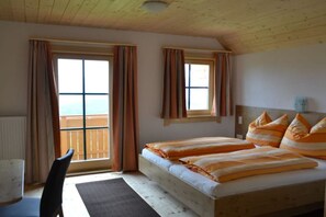 Ein Schlafzimmer mit einem Bett, einem Sessel und Blick ins Freie.