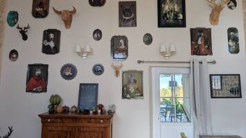 A room with a wooden cabinet, a door with a view, and various wall-mounted decorations including animal horns and framed pictures.