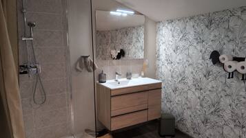 Une salle de bain avec une douche à parois de verre, un lavabo blanc et un miroir.