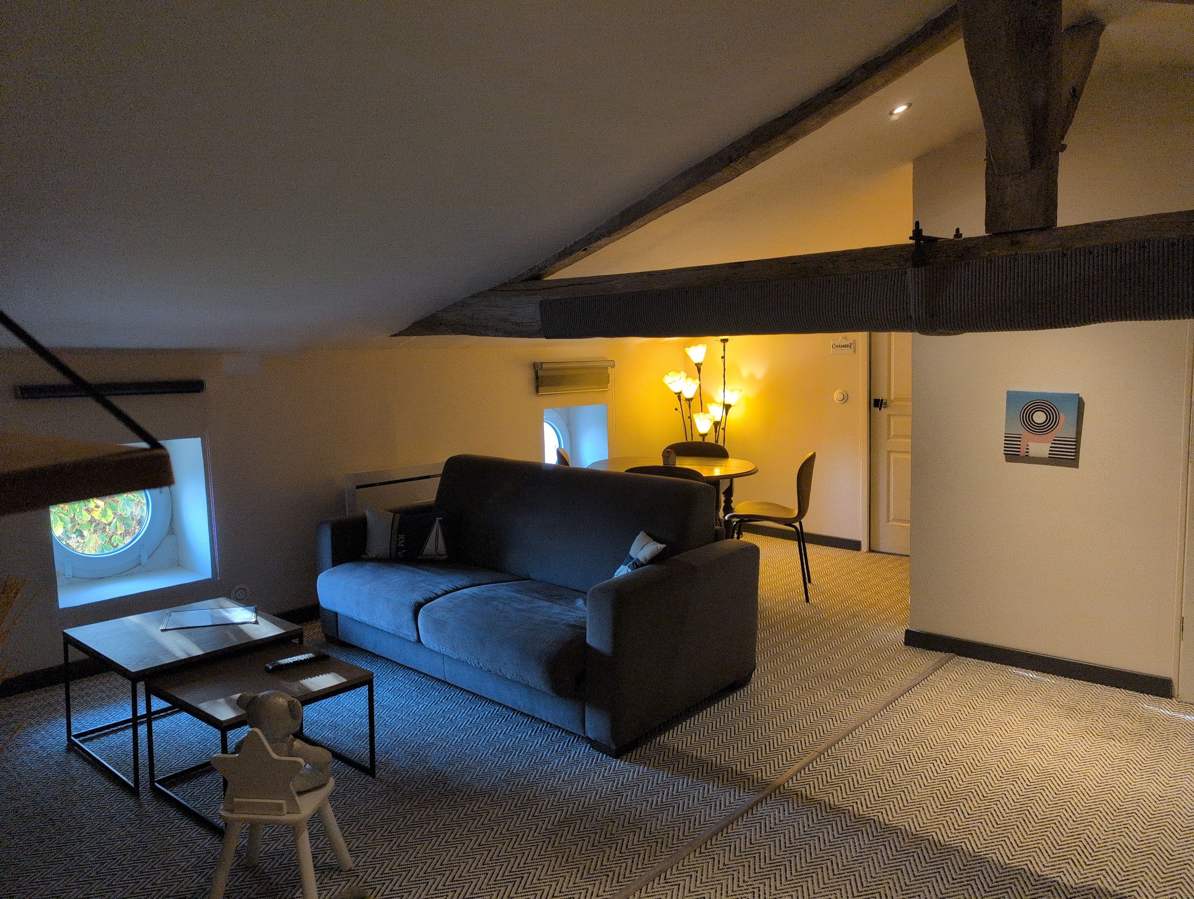 Een gezellige kamer met een bank, een tafeltje, een stoel en een raam met uitzicht.