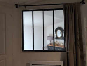 A room with a window, a mirror, and a dresser with decorative items.