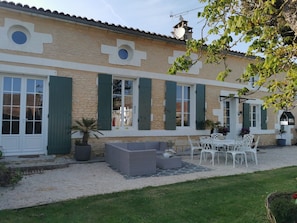 A building with a stone facade, green shutters, and a patio area with outdoor furniture. - Bed and Breakfast 'Suite Familiale' with Shared Pool, Shared Terrace and Wi-Fi (La Devise)