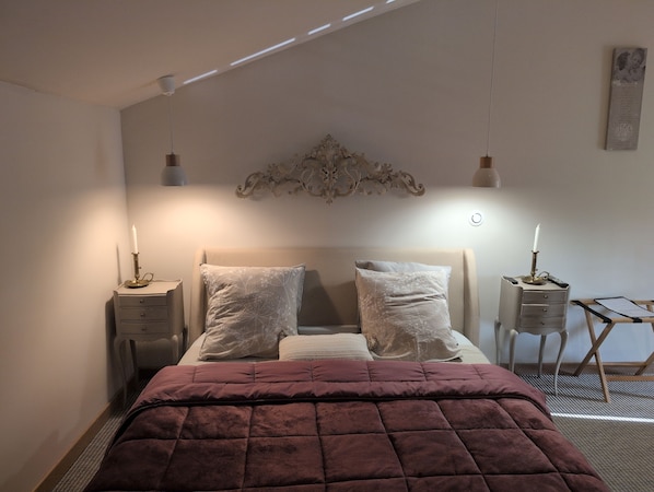 A bedroom with a bed, two bedside tables, a nightstand, a decorative wall piece, and a small desk with a chair. - Bed and Breakfast 'Suite Familiale' with Shared Pool, Shared Terrace and Wi-Fi (La Devise)