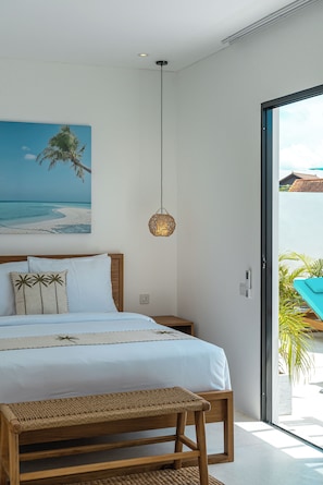 A bedroom with a bed, a hanging light fixture, a bench, and a view of the outdoors. - Villa Dara & Villa Irena (Canggu)