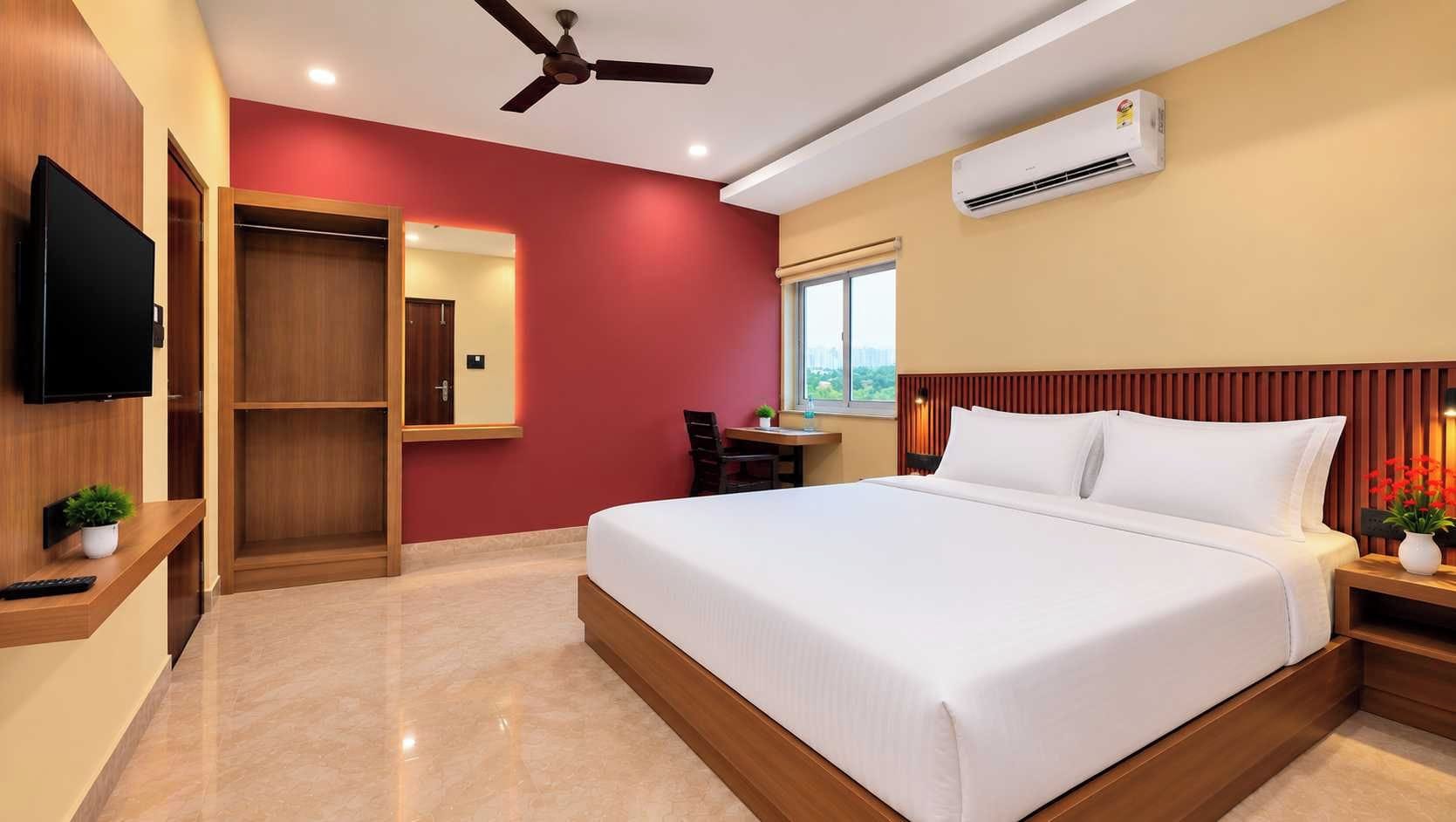 Una habitación de hotel con cama, escritorio, televisor y aire acondicionado.