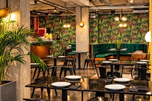 A restaurant interior with a bar area, seating arrangements, and a green upholstered sofa. - Max Brown Hotel Downtown, part of Sircle Collection - Suite (Athens)