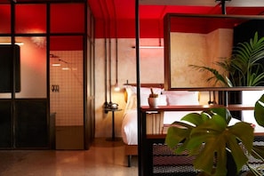 A hotel room with a bed, bedside table, and a potted plant. - Max Brown Hotel Downtown, part of Sircle Collection - Suite (Athens)