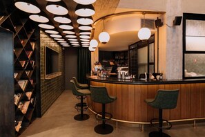 A bar area with a curved counter, multiple stools, and a ceiling with circular light fixtures. - Max Brown Hotel Downtown, part of Sircle Collection - Suite (Athens)
