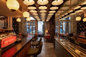 A bar area with multiple seating options, a counter with a red appliance, and a view through the windows. - Max Brown Hotel Downtown, part of Sircle Collection - Suite (Athens)