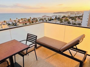 A balcony with a table and two chairs, overlooking a coastal cityscape during sunset. - Rocha Golden Cliff by Agsuites com (Portimão)