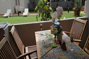 A balcony with a table set for two, featuring a glass top, a potted plant, and a wine glass. - Flat with Pool Views in Corralejo (Corralejo)
