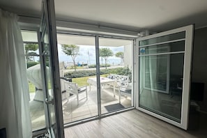 Quarto com porta de vidro deslizante que dá para uma área de pátio externo com mesa e cadeiras.