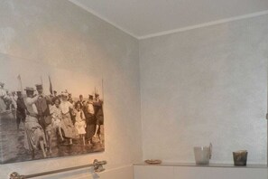 A room with a large black and white photograph on the wall, a small cabinet, and a metal railing. - "Castle by the Sea" - Apt. 02 (Wyk auf Föhr)