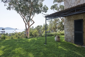 A garden with a large tree, a stone building, and a view of the sea. - Villa 'La Bergerie' with Sea View, Wi-Fi and Air Conditioning (Coti-Chiavari)