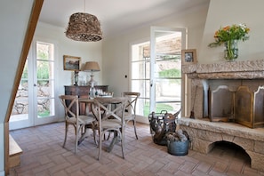 A dining area with a stone fireplace, wooden chairs, and a table set for four. - Villa 'La Bergerie' with Sea View, Wi-Fi and Air Conditioning (Coti-Chiavari)