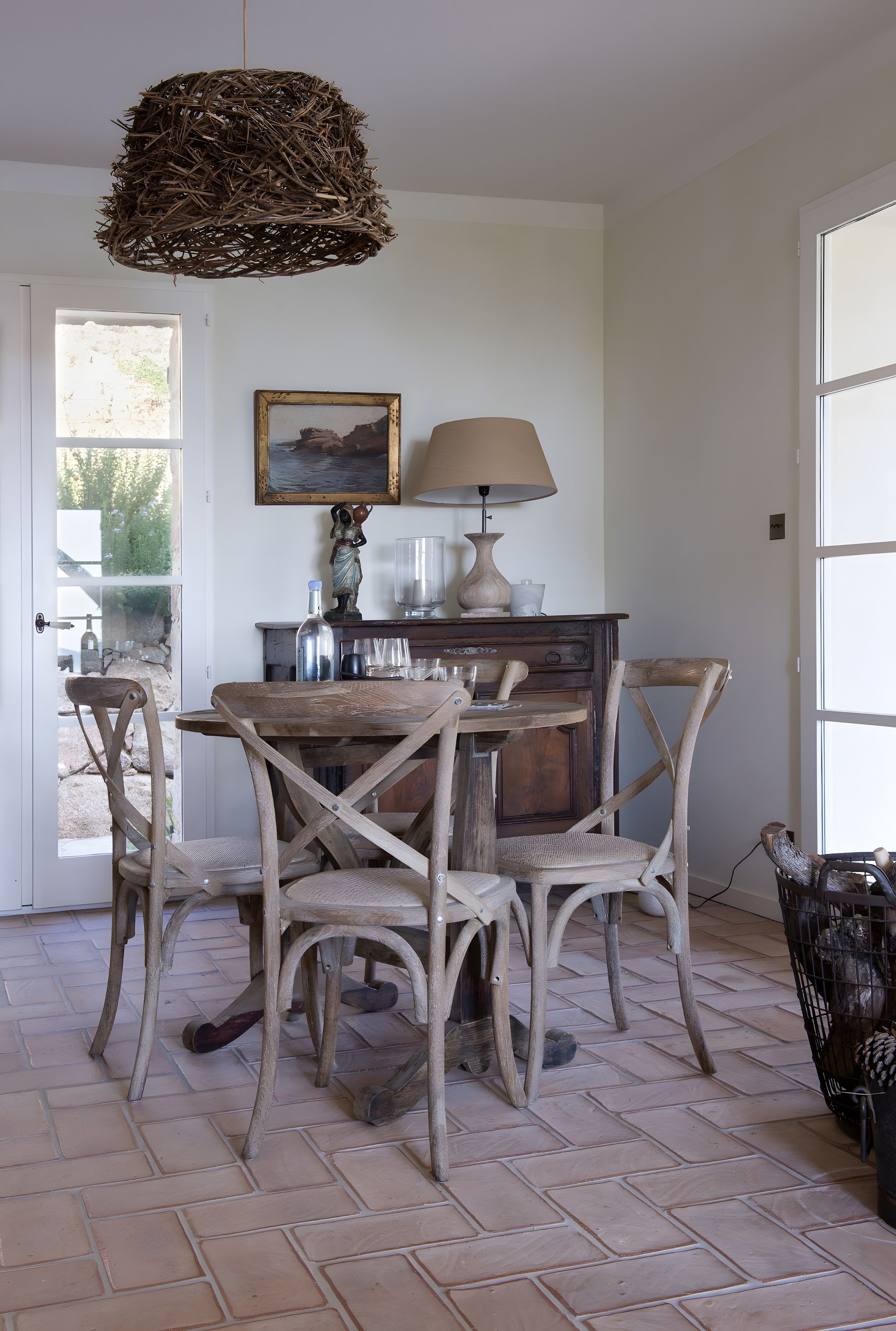 Un coin repas rustique avec une table en bois, des chaises, une lampe et un tableau accroché au mur.